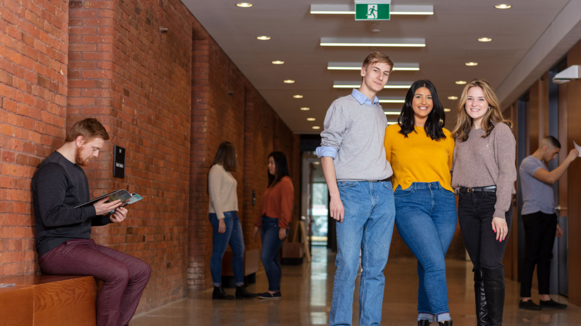 Three students smiling in a hallway